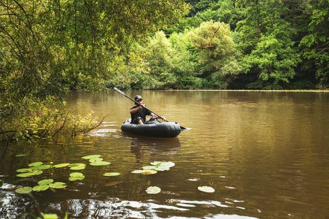 Alan Klee padler en sort Anfibio Nano RTC på en rolig skogsinnsjø. Viser packraftens kompakte størrelse og det innovative RTC-lasterommet i baugen. Foto: Alan Klee.
