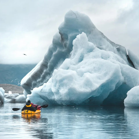 Anfibio Delta MX padles foran et massivt isfjell. En robust ekspedisjons-packraft bygget for å tåle ekstreme forhold og tung oppakning. Foto: Nils Junker.