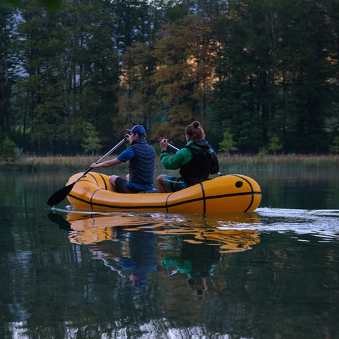 Anfibio Omega C2 packraft padles mot land i et vakkert naturlandskap. Viser sittestilling og padleteknikk for to personer. Foto: Lisa Kristin Schröter.